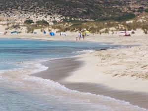 a beach with people standing on the sand and the water at Simosmare Resort in Elafonisos