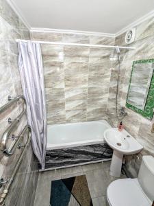 a bathroom with a tub and a toilet and a sink at 3-х комнатная квартира район магазин Радуга in Kostanay