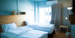 two beds in a hotel room with a window at KENCOZY accommodation in Bangkok