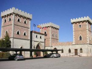 un gran castillo con dos torres con coches aparcados delante en El Torreon del Miguelete, en Miguel Esteban