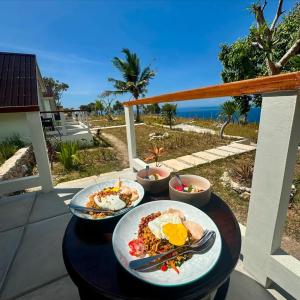 two plates of breakfast food on a table on a balcony at Aloka Penida in Klungkung