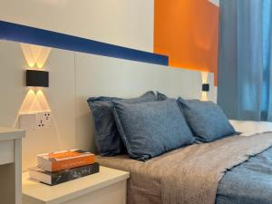 a bedroom with a bed with blue pillows at X - The Subiaco - Edumetro Subang Jaya in Subang Jaya
