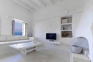 a white living room with a white couch and a tv at MELANOPETRA boutique apartments in Emporeiós