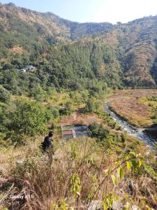 een man die op een heuvel staat met uitzicht op een rivier bij Nature valley home stay in Marchula