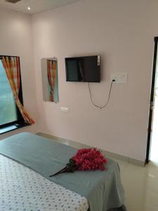 Un dormitorio con una cama y un televisor en la pared. en Alibaug Homestay by Weekend Thrills, en Alibaug