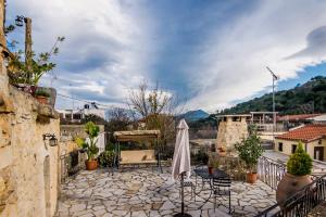 a patio with an umbrella and chairs on a stone floor at Vafes Traditional Stone Houses in Vafés