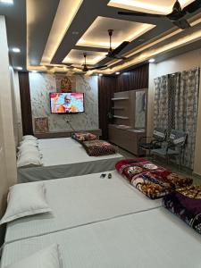 a hotel room with three beds and a flat screen tv at Shri SeetaRam Home Stay Near Shri Ram Janmabhoomi Mandir Ayodhya in Ayodhya
