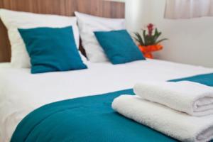 a bed with blue and white sheets and blue pillows at Odalys City Tours Le Jardin des Lettres in Tours