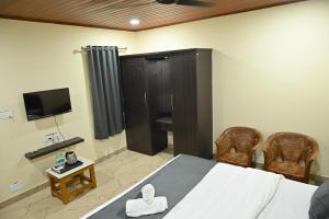 a bedroom with a bed and two chairs and a television at Aarna Coastal Resort in Māvalli
