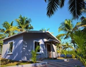 a house on the beach with palm trees at Aarna Coastal Resort in Māvalli