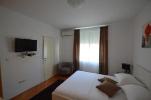 a bedroom with a white bed and a television at Downtown Main Street Studio in Zadar