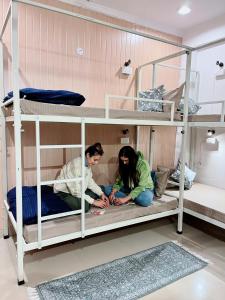 two people sitting on the bottom bunk of a bunk bed at GreenDay Escapes Rishikesh in Rishīkesh