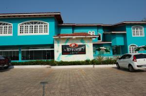 a blue building with a car parked in a parking lot at Santorini Hotel in Santarém