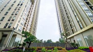 a building with a sign in front of two tall buildings at Comfort Living 2BR at Transpark Cibubur Apartment By Travelio in Depok