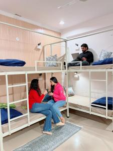 two women sitting on bunk beds in a dorm room at GreenDay Escapes Rishikesh in Rishīkesh