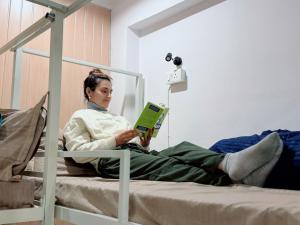 a woman laying on a bed reading a book at GreenDay Escapes Rishikesh in Rishīkesh