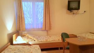 a room with two beds and a table and a tv at Hotel Marco Płońsk Szkolna 115 in Płońsk