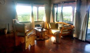 a living room with a couch and a table and windows at Habitación privada en casa rural, vistas Uritorco in Capilla del Monte