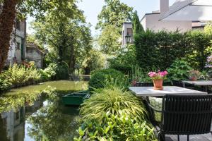 un jardín con estanque, mesa y sillas en B&B Huis Koning, en Brujas