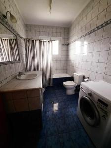 a bathroom with a toilet sink and a washing machine at Enjoy Inn in Néa Karváli