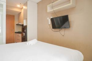 a bedroom with a bed and a tv on the wall at Warm and Cozy Studio at Cinere Bellevue Suites Apartment By Travelio in Depok
