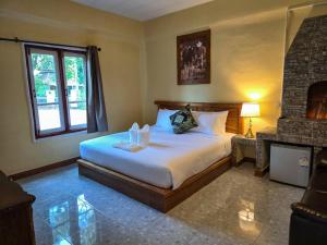 a bedroom with a large bed and a fireplace at Kenikar Raintree Residence Hotel in Chumphon