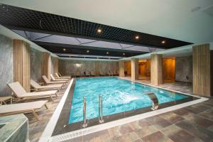 a large swimming pool in a hotel with chairs and tables at Peony Palace Hotel in Kayseri