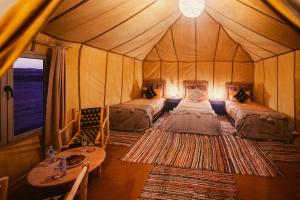 a bedroom with two beds in a tent at Auberge Bivouac La Belle Etoile in Merzouga