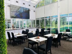 a dining room with tables and chairs and windows at Halfway House Hotel in Kimberley