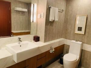a bathroom with a sink and a toilet and a mirror at Oakwood Residence Shanghai in Shanghai