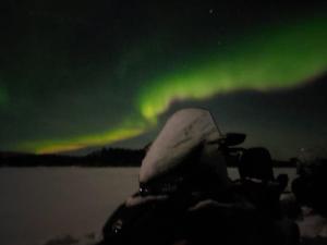 a boat in the water with the aurora in the sky at Luxury City Apartments, Downtown Loft House with Private Sauna in Rovaniemi