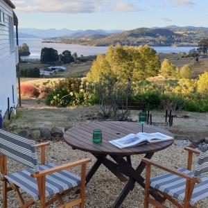 a wooden table with two chairs and a view of the water at Huon Belle Homestead in Waterloo +8 photos