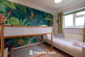 a bedroom with a bunk bed and tropical wallpaper at Spacious, Modern Family Home I Pass the Keys in Pangbourne