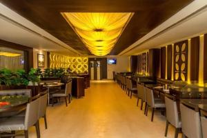 a restaurant with tables and chairs and a yellow ceiling at Hotel Udupi Residency near Shri Krishna Mata, Udupi in Udupi