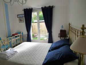 sypialnia z łóżkiem z niebieskimi zasłonami i oknem w obiekcie Villa Alluro w mieście Andernos-les-Bains