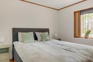 a white bedroom with a large bed with two pillows at The Copper Cottage in Löddeköpinge