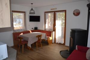 Un comedor con mesa y sillas y un televisor. en Casa del bosco, en Canazei