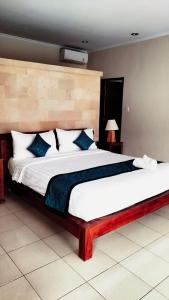 a bedroom with a large white bed with blue pillows at The Green Kamboja Villa in Sanur +26 photos