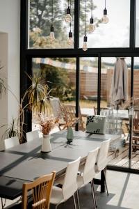 a dining room table with white chairs and a large window at Gîte Ciel - 1-8 pers, au calme, à 20 mins du Puy-de-Dôme, Vulcania et le volcan de Lemptégy in Gelles