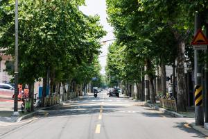 a tree lined street with a motorcycle driving down the street at Local Stitch Creator Town Seogyo in Seoul +112 photos