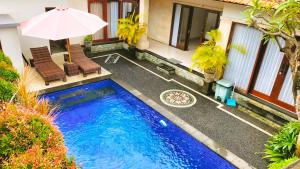 a swimming pool with two chairs and an umbrella at The Green Kamboja Villa in Sanur