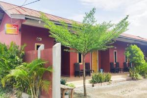 a red house with a tree in front of it at RedDoorz at Morowali Sulawesi Tengah in Ulunipa