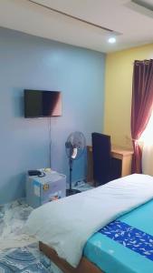 1 dormitorio con 1 cama y escritorio con ventilador en Pollyjolly Hotel And Suites, en Oba Ile