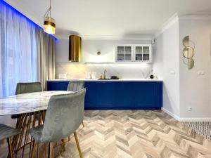 a kitchen with blue cabinets and a table and chairs at Belle View- Central Old Town Apartment AC Progres in Toruń