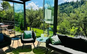 a living room with a couch and chairs and a large window at Cazare Colibița Casa Lipan cu jacuzzi, foișor și loc de joacă in Colibiţa