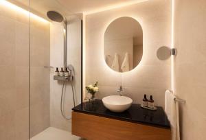 a bathroom with a sink and a shower with a mirror at NH Collection Gent in Ghent