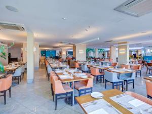 Un comedor con mesas y sillas en un restaurante. en Mercure Rio de Janeiro Barra da Tijuca, en Río de Janeiro