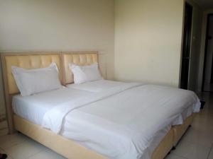 a bed with white sheets and pillows in a room at Apartment Elvis Tower Cikarang in Pegadungan +3 photos