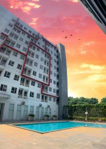 a building with a pool in front of a sunset at Apartment Elvis Tower Cikarang in Pegadungan