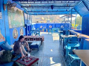Una mujer sentada en un banco en una habitación azul. en Cosy Guest House, en Jodhpur